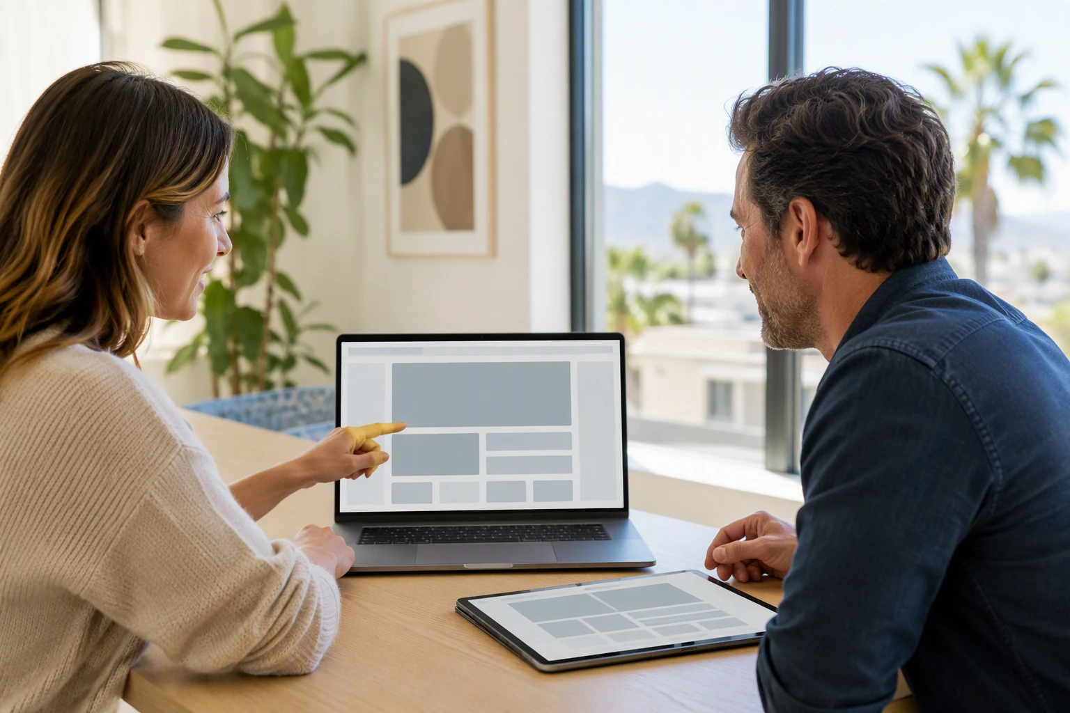 Small Business Websites: 8 Pages Every Owner Needs Small business owner reviewing homepage layout with designer in bright office