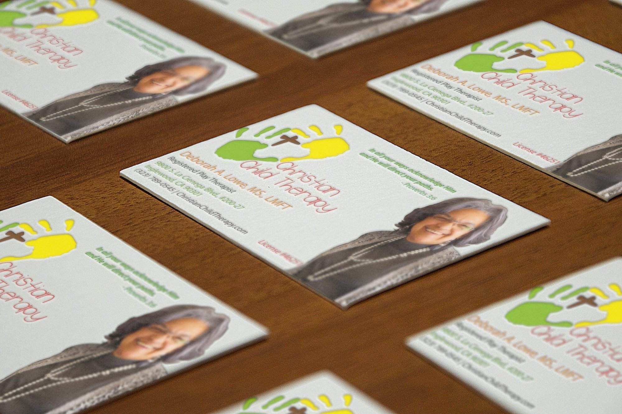 Portfolio Several business cards for “Christian Child Therapy,” featuring a photo of a woman, contact details, and a colorful logo, are arranged on a wooden surface—perfect inspiration for small business website design or local WordPress web designer services.All-inclusive Website Design Services