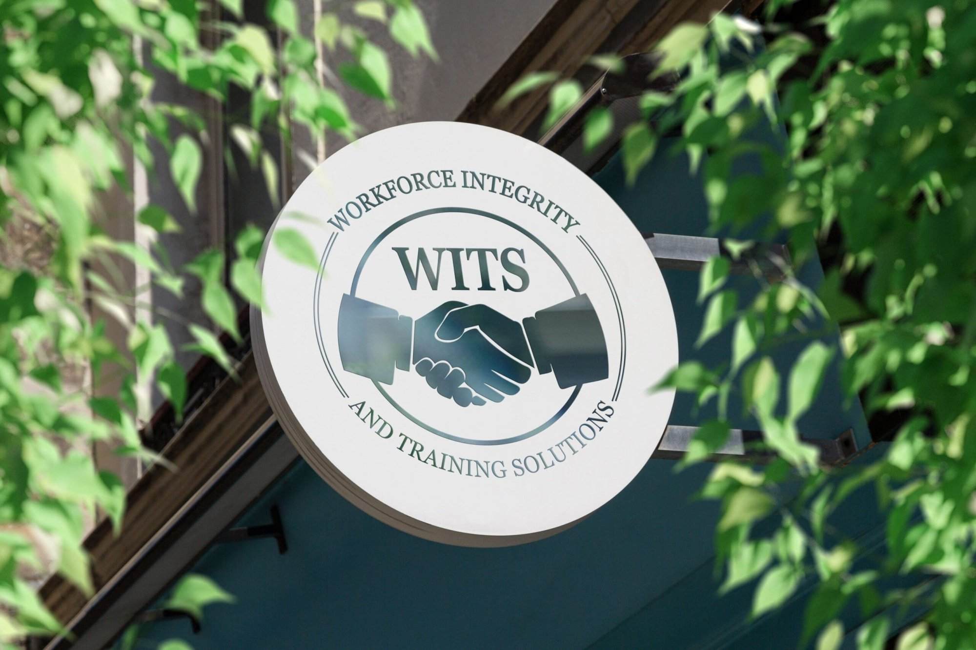 Portfolio A round sign reads “Workforce Integrity and Training Solutions WITS” with an image of two hands shaking, mounted on a building. Framed by green leaves, it hints at the trust you’d expect from a professional website design company.All-inclusive Website Design Services