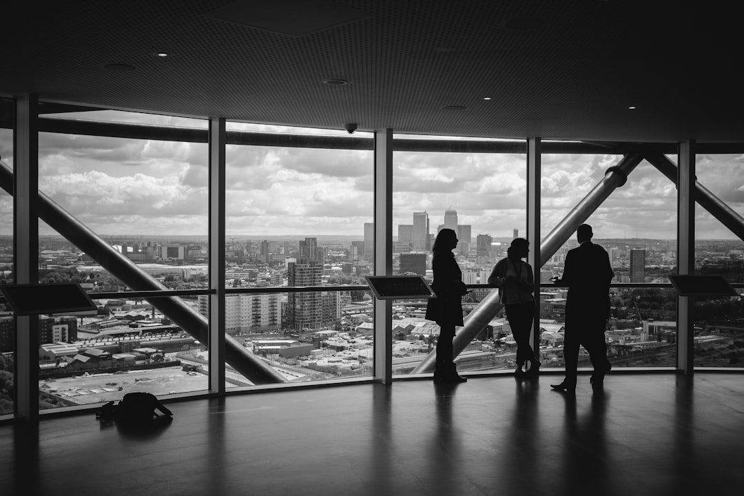 Optimizing Website Content: Integrating SEO Practices Four people stand and talk in front of large windows overlooking a city skyline, perhaps strategizing with a professional website design company on affordable web design services for their next project.