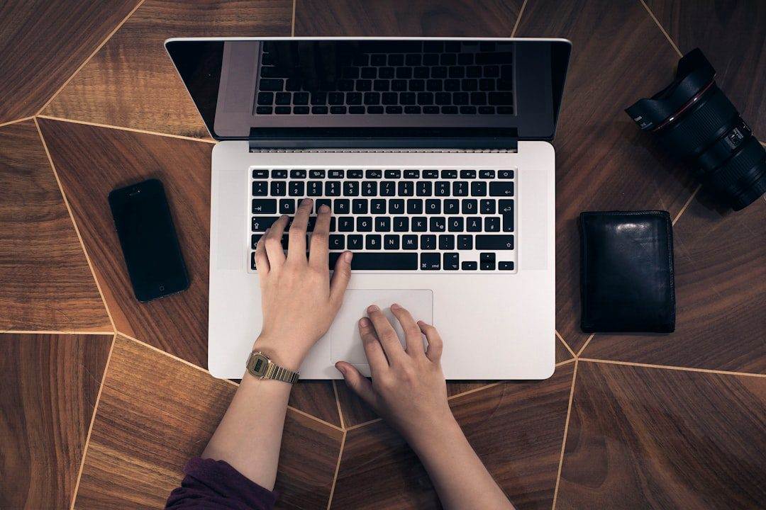 5 Essential Tips for Selecting a Reliable Website Security Provider A person types on a laptop placed on a wooden surface, surrounded by tools for creativity—perfect inspiration for web designer near me or small business website design services.