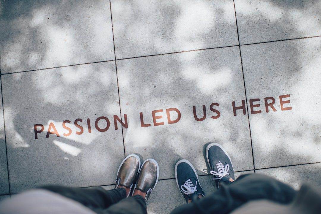 Two people stand on a sidewalk with the words 