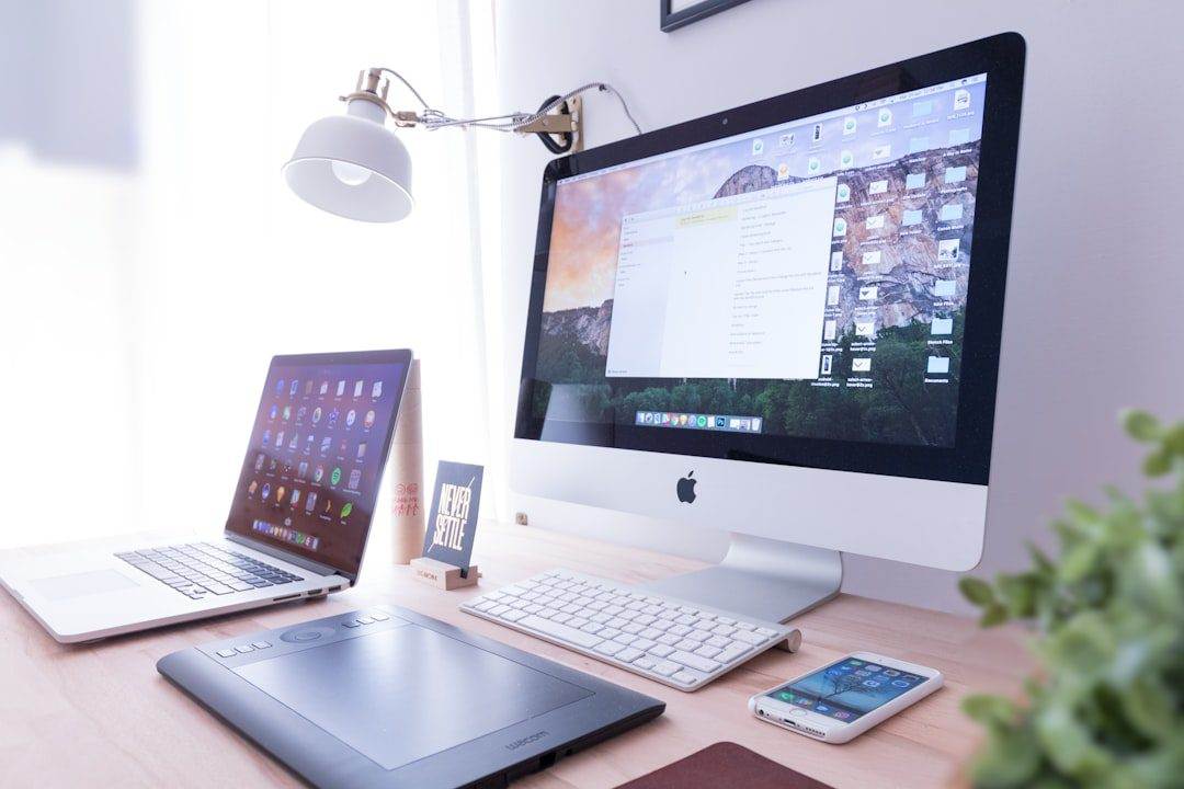 Ultimate Guide to Setting Up Domain-Branded Email Accounts A desktop setup with an iMac, MacBook, graphic tablet, smartphone, keyboard, mouse, desk lamp, and a plant on a wooden desk—ideal for any web designer near me looking for affordable web design services.