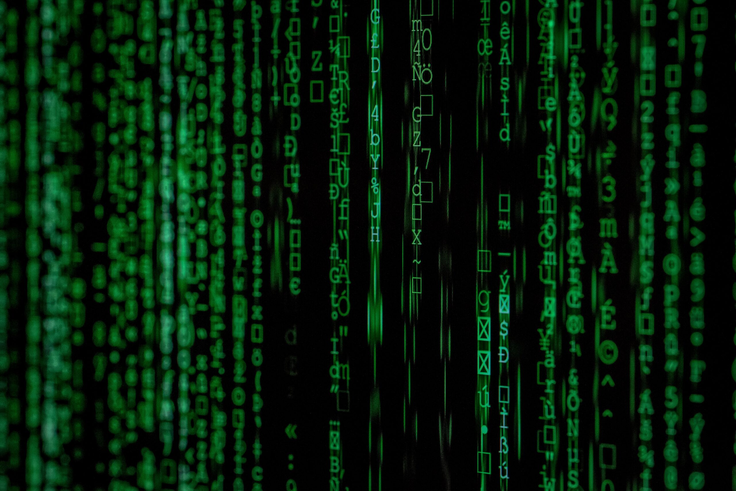 Green digital code characters cascade vertically on a black background, resembling a computer or matrix-style interface.